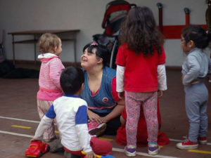 Chica con síndrome de Down cuidando niños en una guarderia.