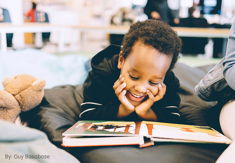 Un niño de origen afroamericano lee un libro sobre diversidad cognitiva