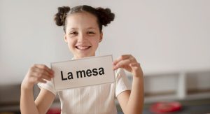 Una niña muestra una targeta con la palabra "mesa" para aprender a leer con el método global de lectura.