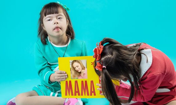 Unas niñas con síndrome de Down utilizan tarjetas con la palabra "mamá" y la imagen de su madre para aprender a leer con los beneficios del método global de lectura.